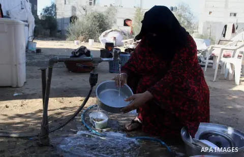 A Palestinian woman from Abu Jamea family washes pots outside her house which was destroyed during the 50-day war between Israel and Hamas militants in the summer of 2014, on in Khan Younis in the southern Gaza Strip Dec...