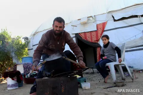 Palestinian Ziad Abu Jamea, cooks with his wife on firewood outside their house which was destroyed during the 50-day war between Israel and Hamas militants in the summer of 2014, on in Khan Younis in the southern Gaza S...