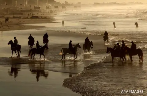 Palestinian men ride their horse as they enjoy the last sunset of 2016 at the beach of Gaza city, on the December 31, 2016. Photo by Ashraf Amra