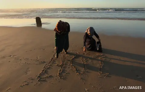 Palestinian girls write on a sand read "2017" during the last sunset of 2016 on the beach of Gaza City, on December 31, 2016. Photo by Ashraf Amra