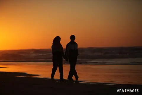 Palestinians walk on the beach of Gaza City, during the last sunset of 2016, on December 31, 2016. Photo by Ashraf Amra