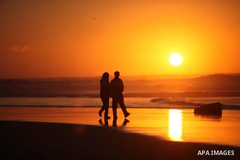 Palestinians walk on the beach of Gaza City, during the last sunset of 2016, on December 31, 2016. Photo by Ashraf Amra