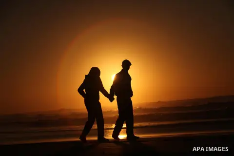 Palestinians walk on the beach of Gaza City, during the last sunset of 2016, on December 31, 2016. Photo by Ashraf Amra
