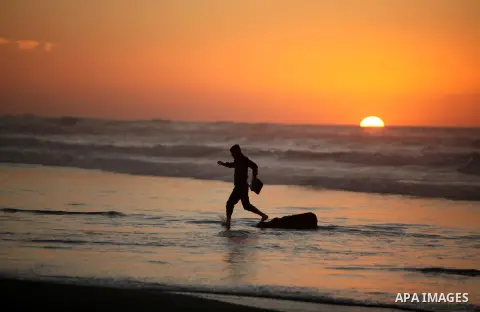 A Palestinian man walks on the beach of Gaza City, during the last sunset of 2016, on December 31, 2016. Photo by Ashraf Amra