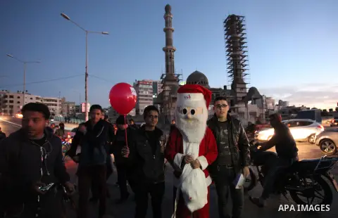 A Palestinian man in Santa Claus costume takes part in the celebration of the New Year at the Gaza seaport, on December 31, 2016. Photo by Ashraf Amra
