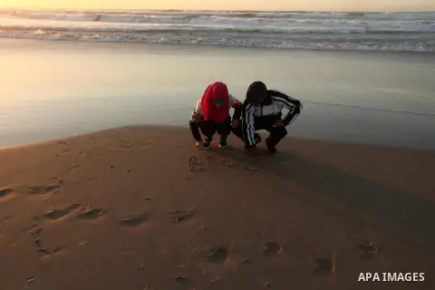 Palestinians write on a sand read "2017" during the last sunset of 2016 on the beach of Gaza City, on December 31, 2016. Photo by Ashraf Amra