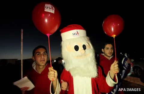 A Palestinian man in Santa Claus costume takes part in the celebration of the New Year at the Gaza seaport, on December 31, 2016. Photo by Ashraf Amra