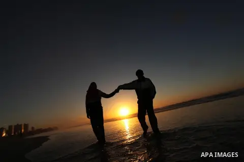 Palestinians walk on the beach of Gaza City, during the last sunset of 2016, on December 31, 2016. Photo by Ashraf Amra