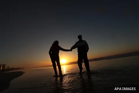 Palestinians walk on the beach of Gaza City, during the last sunset of 2016, on December 31, 2016. Photo by Ashraf Amra
