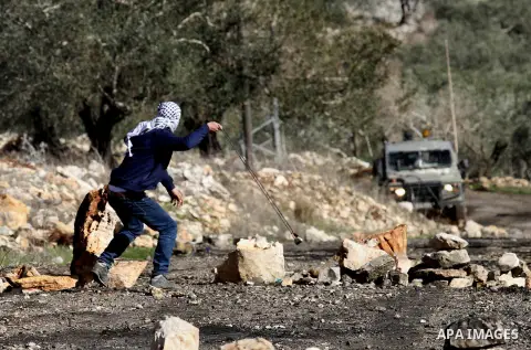 A Palestinian protester uses aslingshot to hurl stones towards Israeli security forces during clashes following a demonstration against the expropriation of Palestinian land by Israel in the village of Kfar Qaddum, near...
