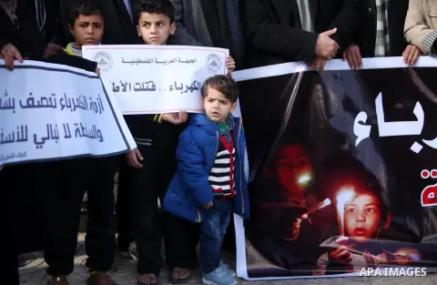 Palestinians hold placards during a demonstration against the ongoing electricity shortages in Gaza city on January 15, 2017. Power shortages in the Palestinian enclave have occurred repeatedly in recent weeks, with home...