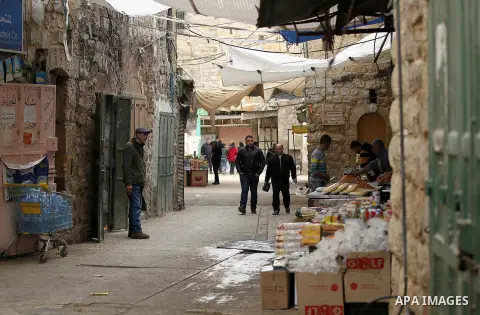 Palestinians walk at a market in the Old City of the West Bank town of Hebron, on January 25, 2017. Photo by Wisam Hashlamoun