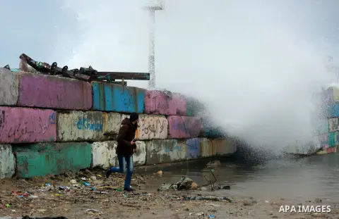 A Palestinian man runs as a huge wave crash over a sea wall at the Gaza seaport during a rainy and heavy wind weather prevails on the Mediterranean Sea, in Gaza City on January 28, 2017. Photo by Mohammed Asad