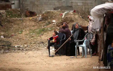 Palestinian women sit outside a hovel during the cold weather in the Jabalia refugee camp in the northern Gaza Strip on January 29, 2017. Photo by Ashraf Amra