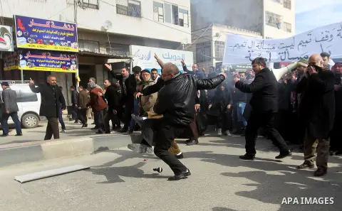 Palestinian protesters run for cover during clashes with Palestinian policemen following a demonstration against a decision by the Palestinian Authority to grant a public land to the Russian church, in the West Bank city...