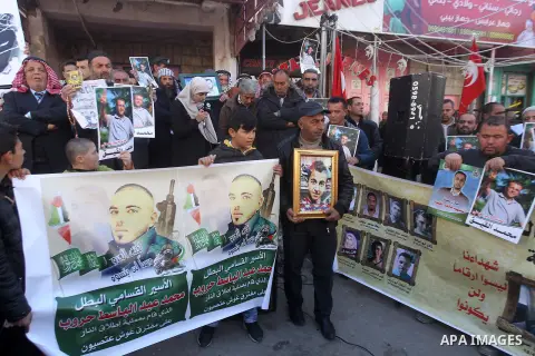 Palestinians hold posters bearing a portrait of Palestinian journalist Mohammed al-Qiq who is imprisoned in an Israeli jail during a protest in the West Bank city of Hebron, on February 10, 2017. Photo by Wisam Hashlamou...