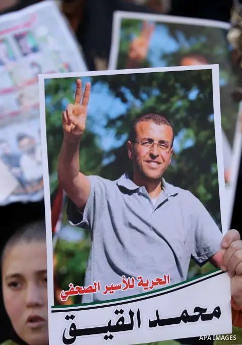 Palestinians hold posters bearing a portrait of Palestinian journalist Mohammed al-Qiq who is imprisoned in an Israeli jail during a protest in the West Bank city of Hebron, on February 10, 2017. Photo by Wisam Hashlamou...