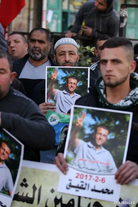Palestinians hold posters bearing a portrait of Palestinian journalist Mohammed al-Qiq who is imprisoned in an Israeli jail during a protest in the West Bank city of Hebron, on February 10, 2017. Photo by Wisam Hashlamou...