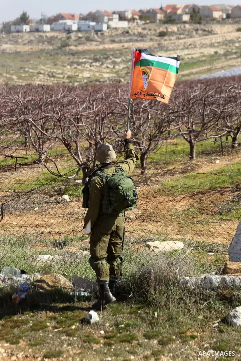 An Israeli border policeman removes the Palestine flag during a demonstration against the construction of Jewish settlements in the occupied West Bank city of Hebron, on February 10, 2017. Photo by Wisam Hashlamoun