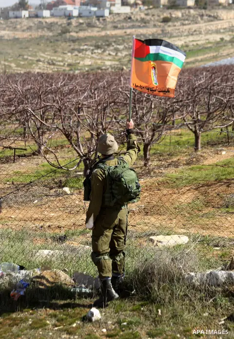 An Israeli border policeman removes the Palestine flag during a demonstration against the construction of Jewish settlements in the occupied West Bank city of Hebron, on February 10, 2017. Photo by Wisam Hashlamoun