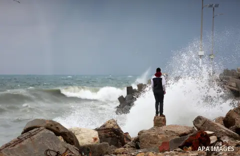 A Palestinian man stands on a stone at the Gaza seaport during a rainy day in Gaza City on February 14, 2017. Photo by Mohammed Asad