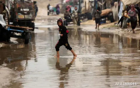 A Palestinian boy walks in a flooded area following heavy rainfall in the al-Moghraqa in the center Gaza Strip, on February 16, 2017. Photo by Ashraf Amra
