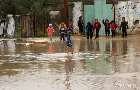 Palestinian children walk in a flooded area following heavy rainfall, in the al-Moghraqa in the center Gaza Strip, on February 16, 2017. Photo by Ashraf Amra
