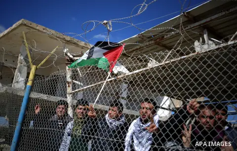Palestinians stand behind a fence as they wait for the arrival of their relatives at Rafah crossing after it was opened by Egyptian authorities to allow stranded Palestinians to return to Gaza, in the southern Gaza Strip...