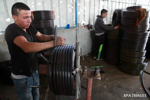 A Palestinian worker reuses plastics and metals to produce water hoses at a factory, in Gaza city, February 22, 2017. Workers collect the household recyclables, metals and plastic from landfill and garbage to sell to the...