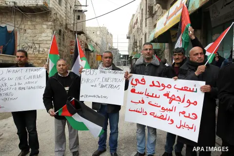 Palestinian protesters hold placards during a demonstration against the closure of Shuhada street, on the 23rd anniversary of the closure, on February 22, 2017 in the West Bank city of Hebron. On February 25, 1994 Israel...
