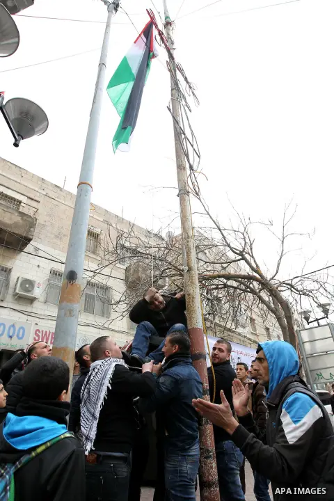 A Palestinian protester raises a palestinian flag during a demonstration against the closure of Shuhada street, on the 23rd anniversary of the closure, on February 22, 2017 in the West Bank city of Hebron. On February 25...