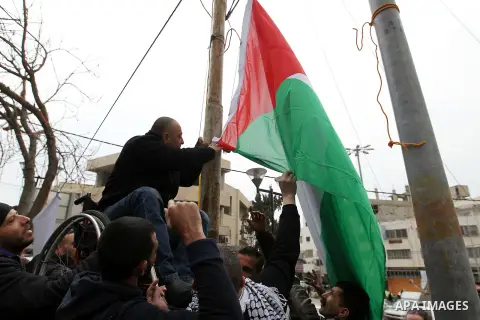 A Palestinian protester raises a palestinian flag during a demonstration against the closure of Shuhada street, on the 23rd anniversary of the closure, on February 22, 2017 in the West Bank city of Hebron. On February 25...