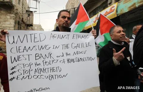 Palestinian protesters hold placards during a demonstration against the closure of Shuhada street, on the 23rd anniversary of the closure, on February 22, 2017 in the West Bank city of Hebron. On February 25, 1994 Israel...