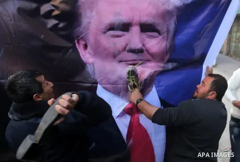 Palestinian demonstrators throw old shoes at a poster of US President Donald Trump as they protest against his support of Israel and demand for the Israeli army to re-open Shuhada Street, which is largely closed off to P...