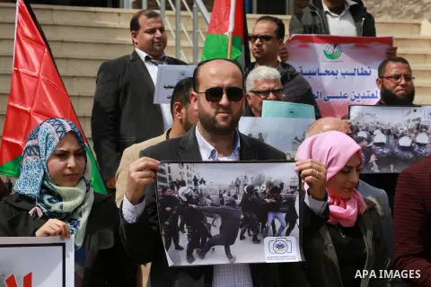 Palestinian journalists hold placards during a protest to show solidarity with their colleges in the West Bank, in front of the Legislative Council, in Gaza city on March 13, 2017. Photo by Mohammed Asad