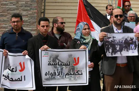 Palestinian journalists hold placards during a protest to show solidarity with their colleges in the West Bank, in front of the Legislative Council, in Gaza city on March 13, 2017. Photo by Mohammed Asad