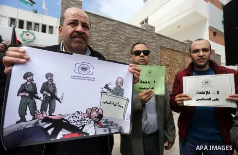 Palestinian journalists hold placards during a protest to show solidarity with their colleges in the West Bank, in front of the Legislative Council, in Gaza city on March 13, 2017. Photo by Mohammed Asad