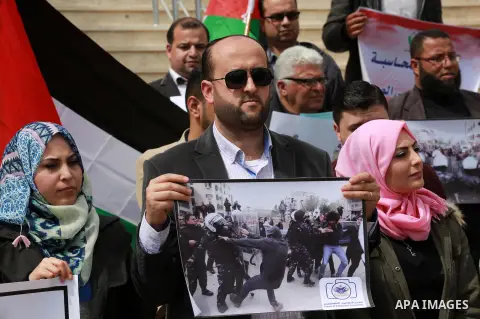Palestinian journalists hold placards during a protest to show solidarity with their colleges in the West Bank, in front of the Legislative Council, in Gaza city on March 13, 2017. Photo by Mohammed Asad