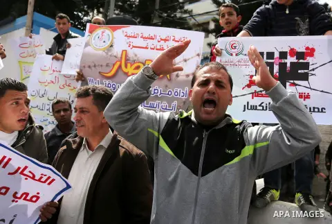 Palestinians hold placards during a protest calling for end the Israeli blockade on Gaza Strip, outside the UN offices, in Gaza city, on March 13, 2017. Photo by Ashraf Amra