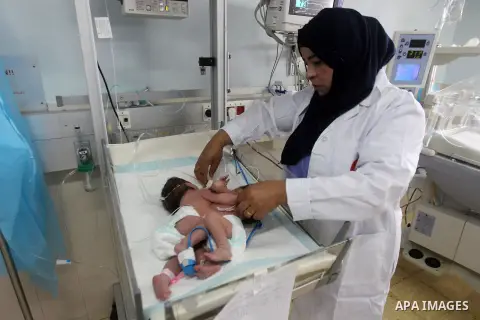 A Palestinian nurse checks on a One-day-old Palestinian conjoined twin boys lie in an incubator at the nursery Hospital in the West Bank city of Hebron, March 16, 2017. Photo by Wisam Hashlamoun