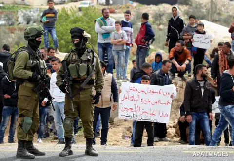 Palestinian protesters hold placards during a protest calling for the reopening of a closed street in the West Bank city of Hebron on March 17, 2017. Photo by Wisam Hashlamoun