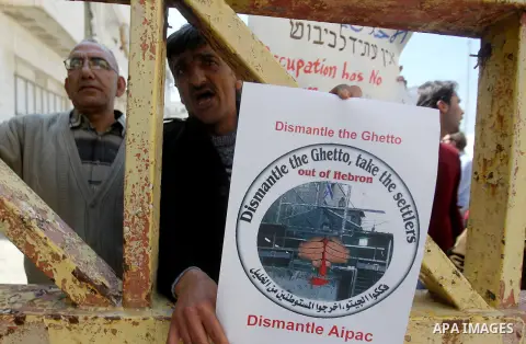 A Palestinian demonstrator holds a placard during a protest against Jewish settlements in the West Bank city of Hebron March 26, 2017. Photo by Wisam Hashlamoun