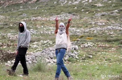 An Israeli settler gives the finger to Palestinian demonstrators during clashes with Israel forces following a protest to mark land day in village of Madama, south of Nablus, on March 30, 2017 in the Israeli occupied Wes...