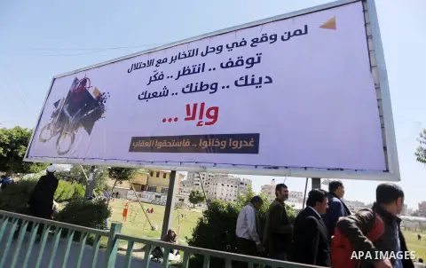 Palestinians walk past a banner announcing the launch of a campaign against collaborating with Israel, in Gaza city, on April 04, 2017, as the ruling Ministry of Interior in the Gaza Strip launches a week-long campaign t...