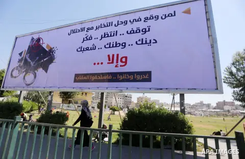 Palestinians walk past a banner announcing the launch of a campaign against collaborating with Israel, in Gaza city, on April 04, 2017, as the ruling Ministry of Interior in the Gaza Strip launches a week-long campaign t...