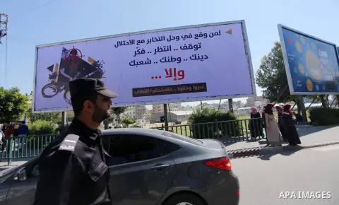 Palestinians walk past a banner announcing the launch of a campaign against collaborating with Israel, in Gaza city, on April 04, 2017, as the ruling Ministry of Interior in the Gaza Strip launches a week-long campaign t...