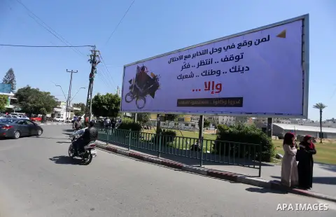 Palestinians walk past a banner announcing the launch of a campaign against collaborating with Israel, in Gaza city, on April 04, 2017, as the ruling Ministry of Interior in the Gaza Strip launches a week-long campaign t...