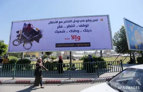 Palestinians walk past a banner announcing the launch of a campaign against collaborating with Israel, in Gaza city, on April 04, 2017, as the ruling Ministry of Interior in the Gaza Strip launches a week-long campaign t...