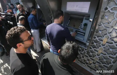 Palestinian employees paid by the Palestinian Authority wait to receive their salaries from an ATM, outside a Bank in Gaza City April 5, 2017. The salaries of Palestinian employees in Gaza strip have been reduced by abou...