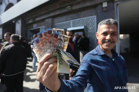 Palestinian employees paid by the Palestinian Authority wait to receive their salaries from an ATM, outside a Bank in Gaza City April 5, 2017. The salaries of Palestinian employees in Gaza strip have been reduced by abou...